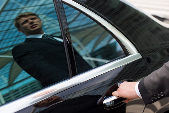 Ein Chauffeur spiegelt sich im Fenster einer Limousine.