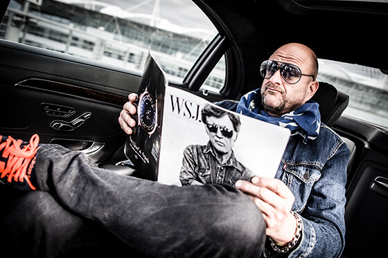 Ein Mann sitzt in einer Limousine und liest ein Magazin.