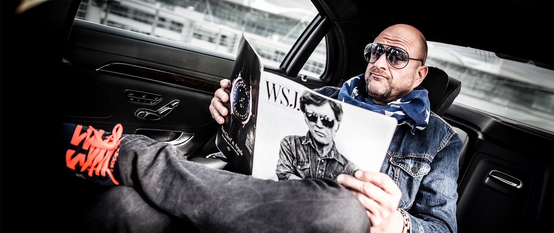 A man sitting in a limousine and reading a magazine.