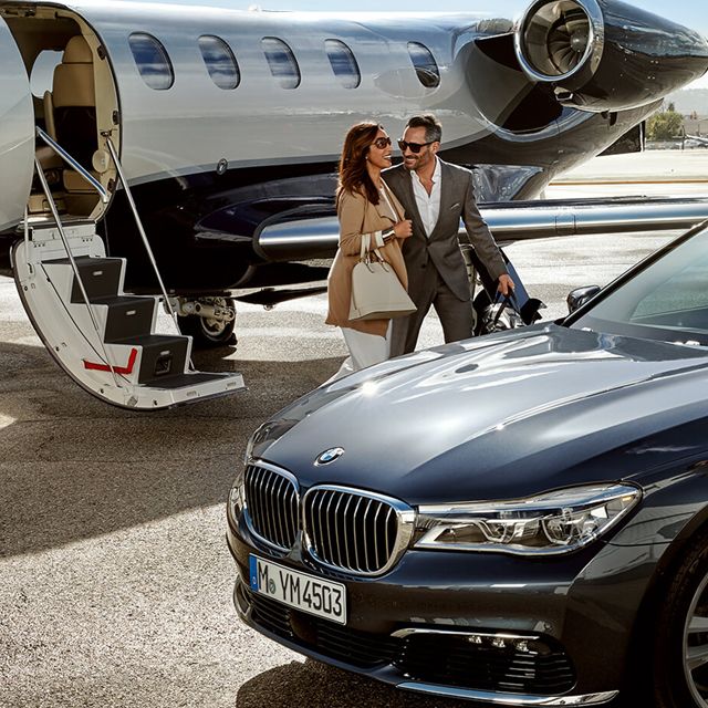 Ein Chauffeur holt mit einer Limousine ein Paar auf dem Rollfeld vom Business-Jet ab.