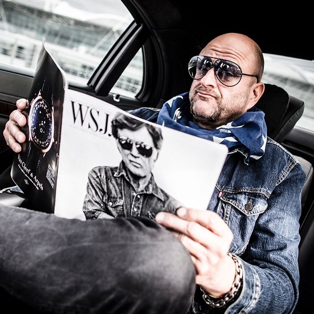 A man sitting in a limousine and reading a magazine.