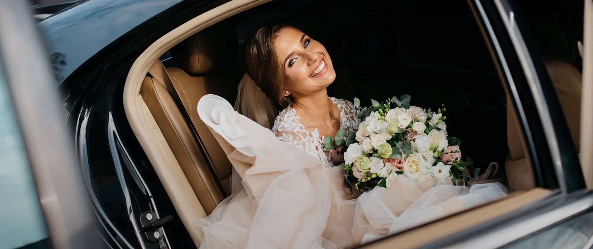 A bride is sitting in a wedding limousine.