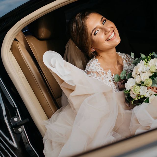 A bride is sitting in a wedding limousine.